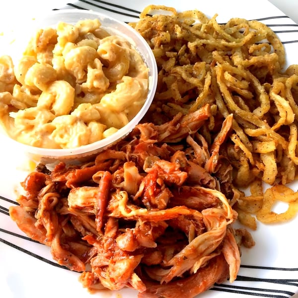 Fat Pete's BBQ platter with mac and cheese, crispy onion strings, and saucy pulled chicken.