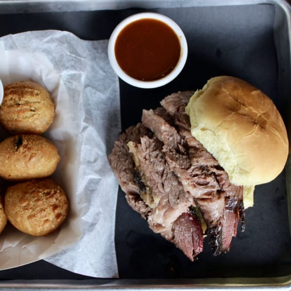 Fat Pete's BBQ brisket sandwich with hush puppies and a side of barbecue sauce.