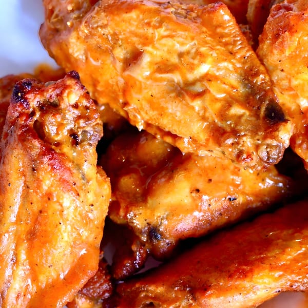 Close-up of several glistening, saucy BBQ chicken wings from Fat Pete's BBQ.